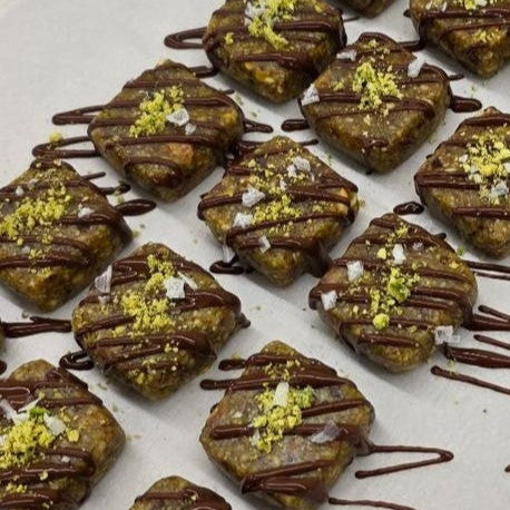 Pistachio Dream dessert squares featuring a rich pistachio base topped with a layer of chocolate, displayed on a white plate